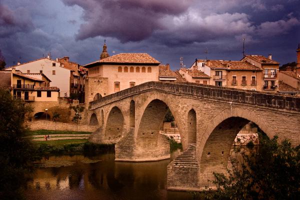 Vista al atardecer del puente románico y pueblo de Puente la Reina